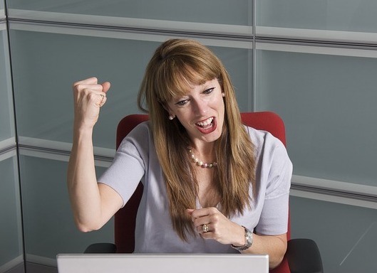 Woman pumping her fist in front of a computer
