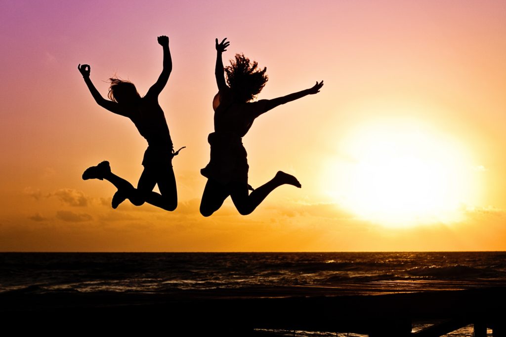 Two women jumping with joy against a sunset